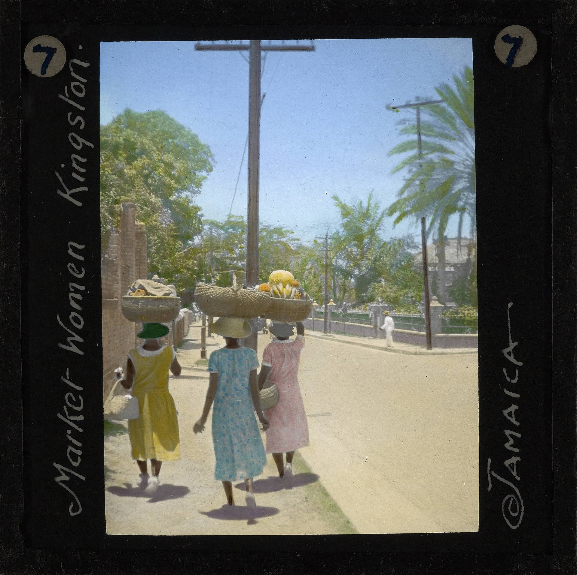 Hand-tinted lantern slide of three market women carrying baskets on their heads, Kingston, early 1900s